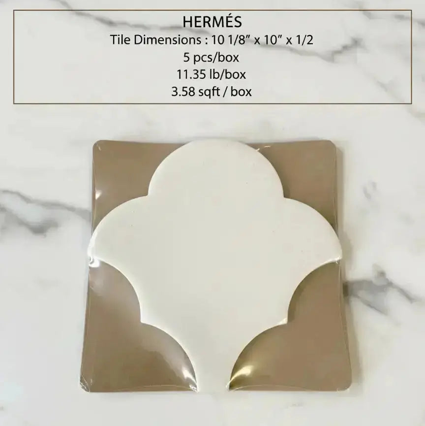 Decorative tile with 'Hermès' branding on a marble background