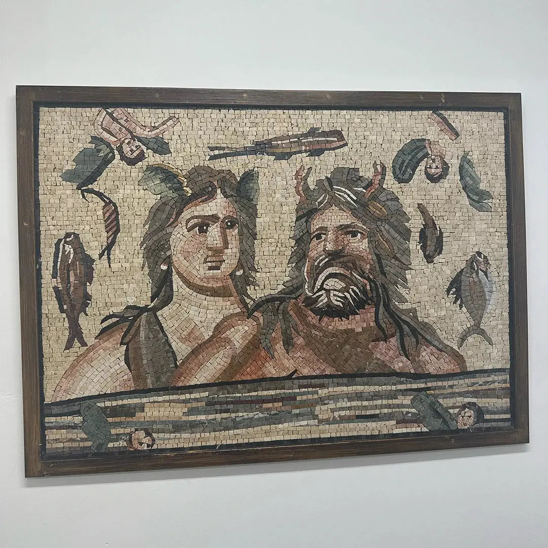 Mosaic artwork of two figures with decorative elements on a plain wall.