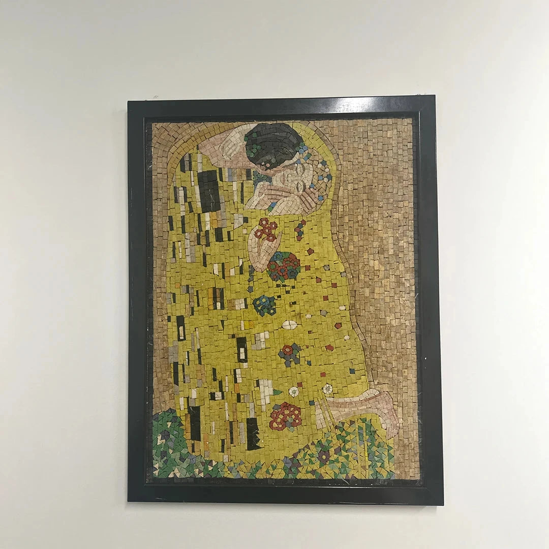 Mosaic artwork of 'The Kiss' by Gustav Klimt in a black frame on a white wall.