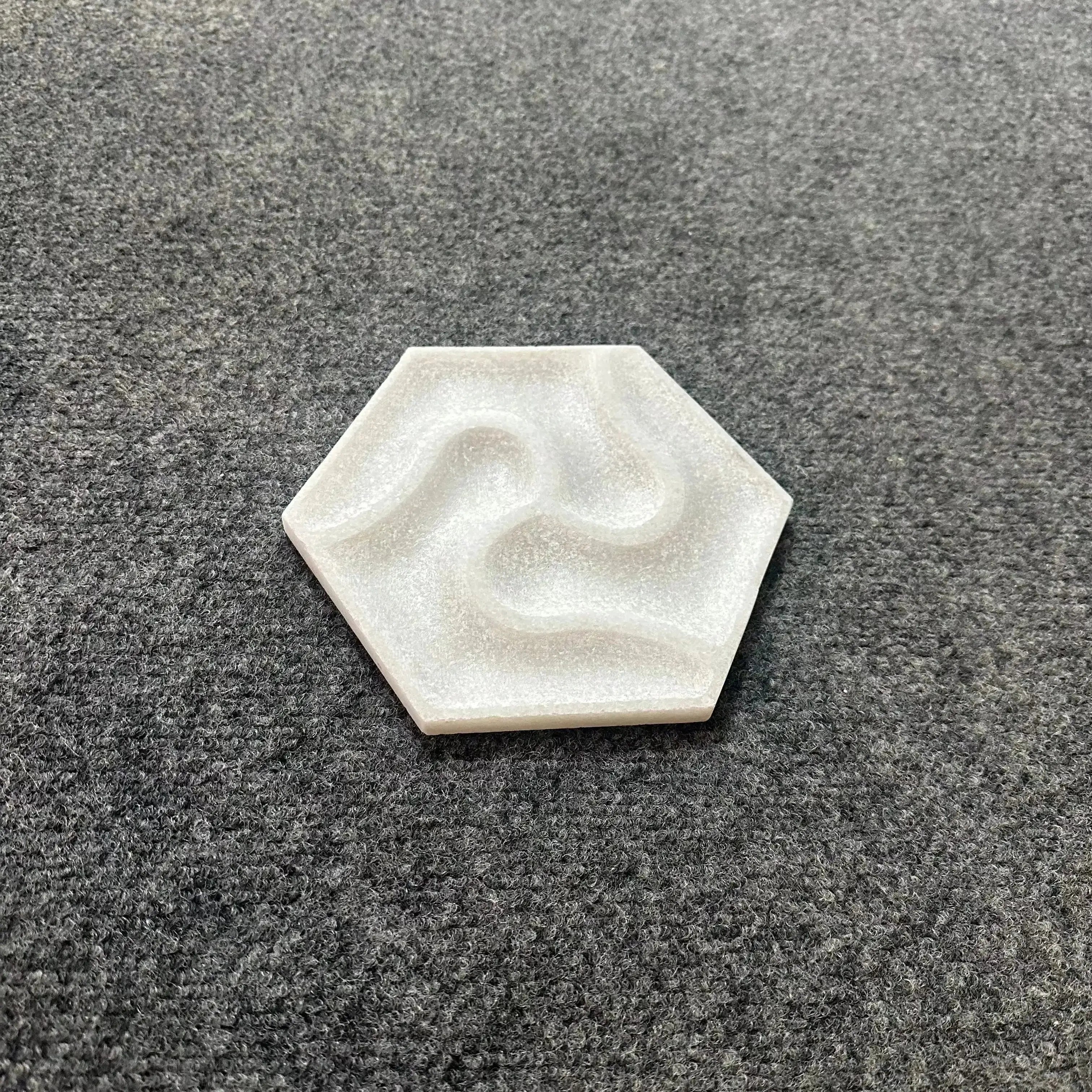 Hexagonal white stone with a wavy pattern on a gray textured surface