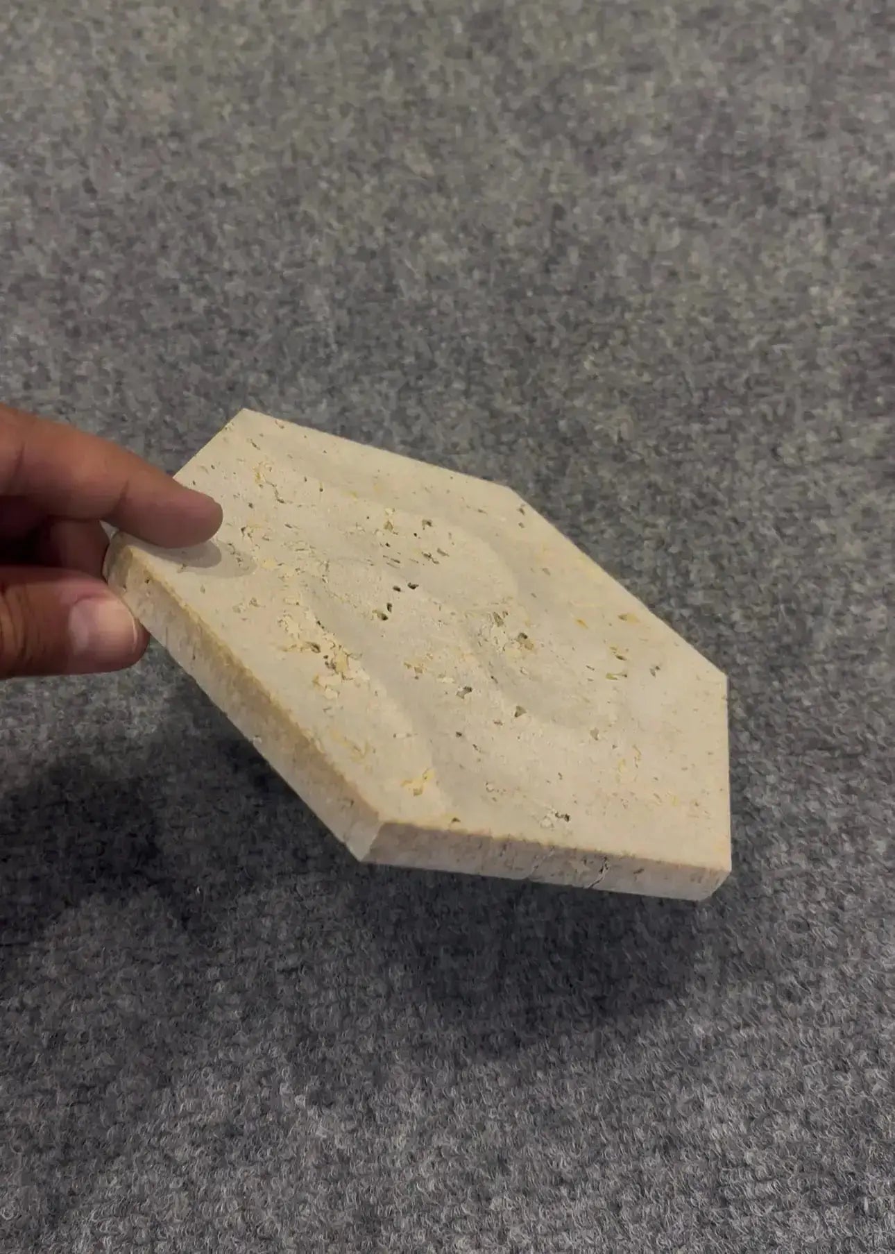 Hexagonal stone block held by a hand on a gray background