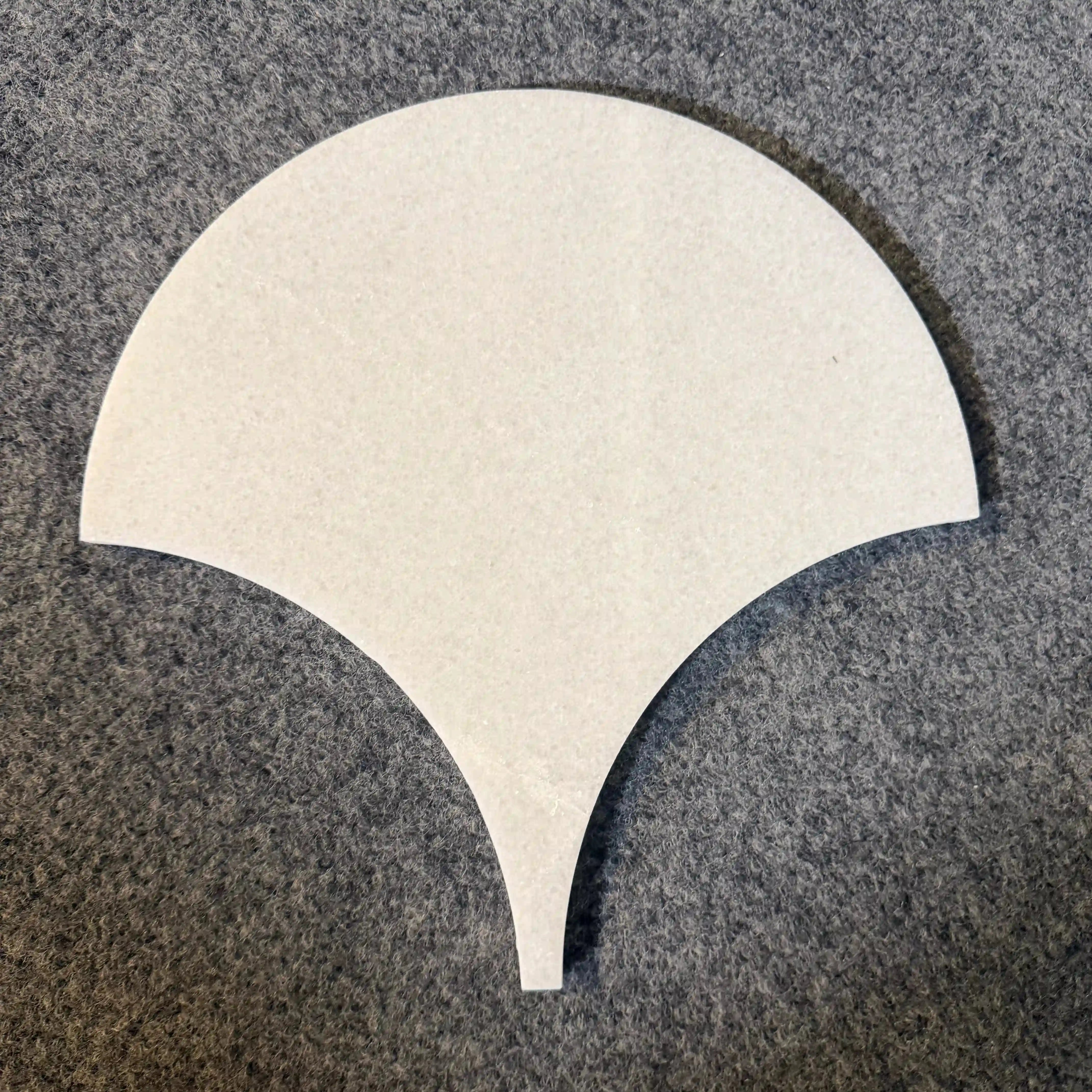 Ebisu natural marble mosaic tile presented as an individual sample piece on a textured gray background, featuring an elegant, fan-shaped or teardrop silhouette with a tapering point in smooth, uniform white marble.