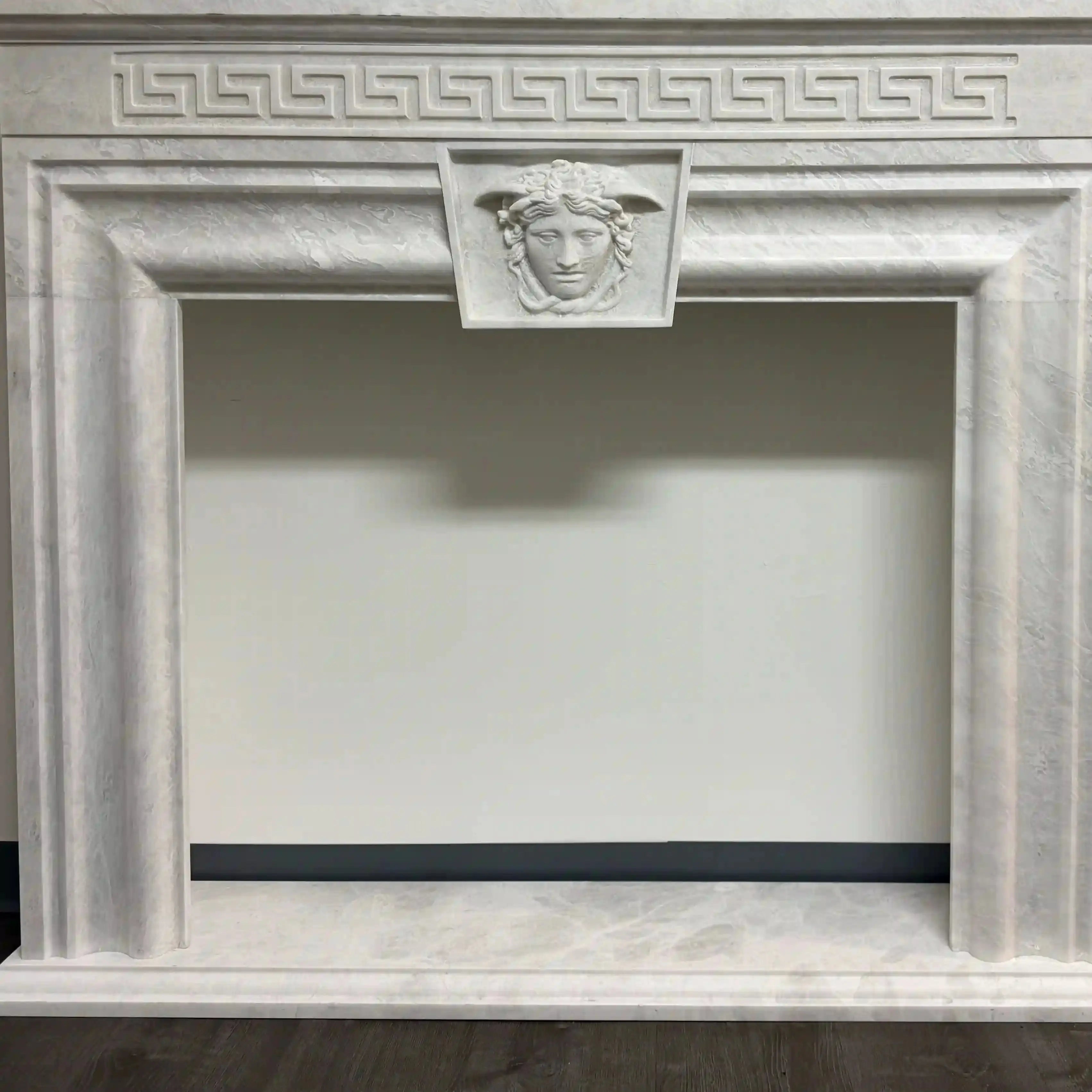 Decorative fireplace with classical design and face emblem.