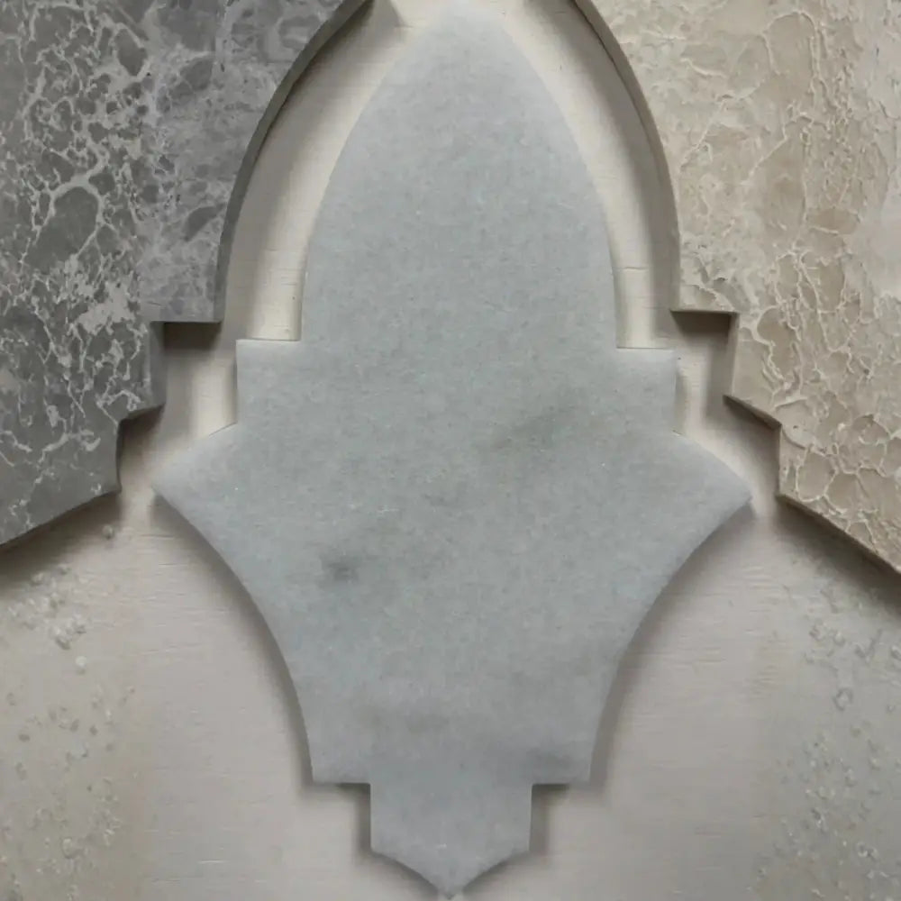 Khepri marble mosaic tile showcasing a close-up detail of an individual interlocking lantern-shaped natural stone unit framed by contrasting marble tiles.