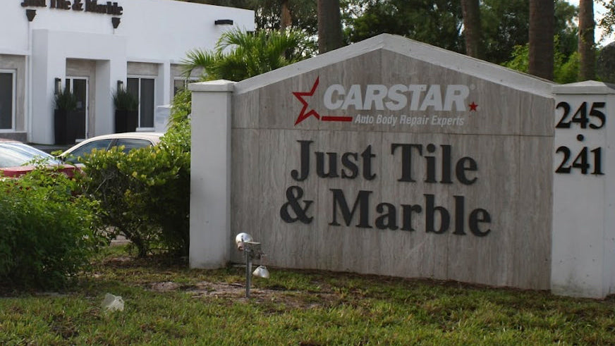Sign for CARSTAR and Just Tile & Marble with a building and trees in the background