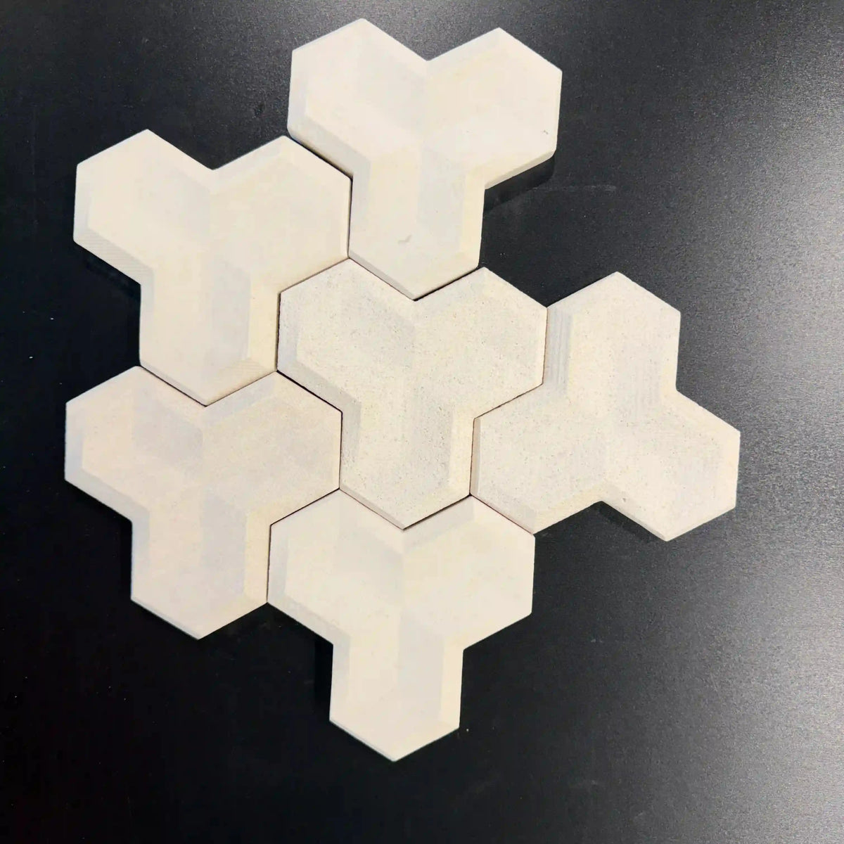 Tabu natural stone 3D wall tile displayed as an arrangement of interlocking geometric Y-shaped light beige panels on a dark surface.