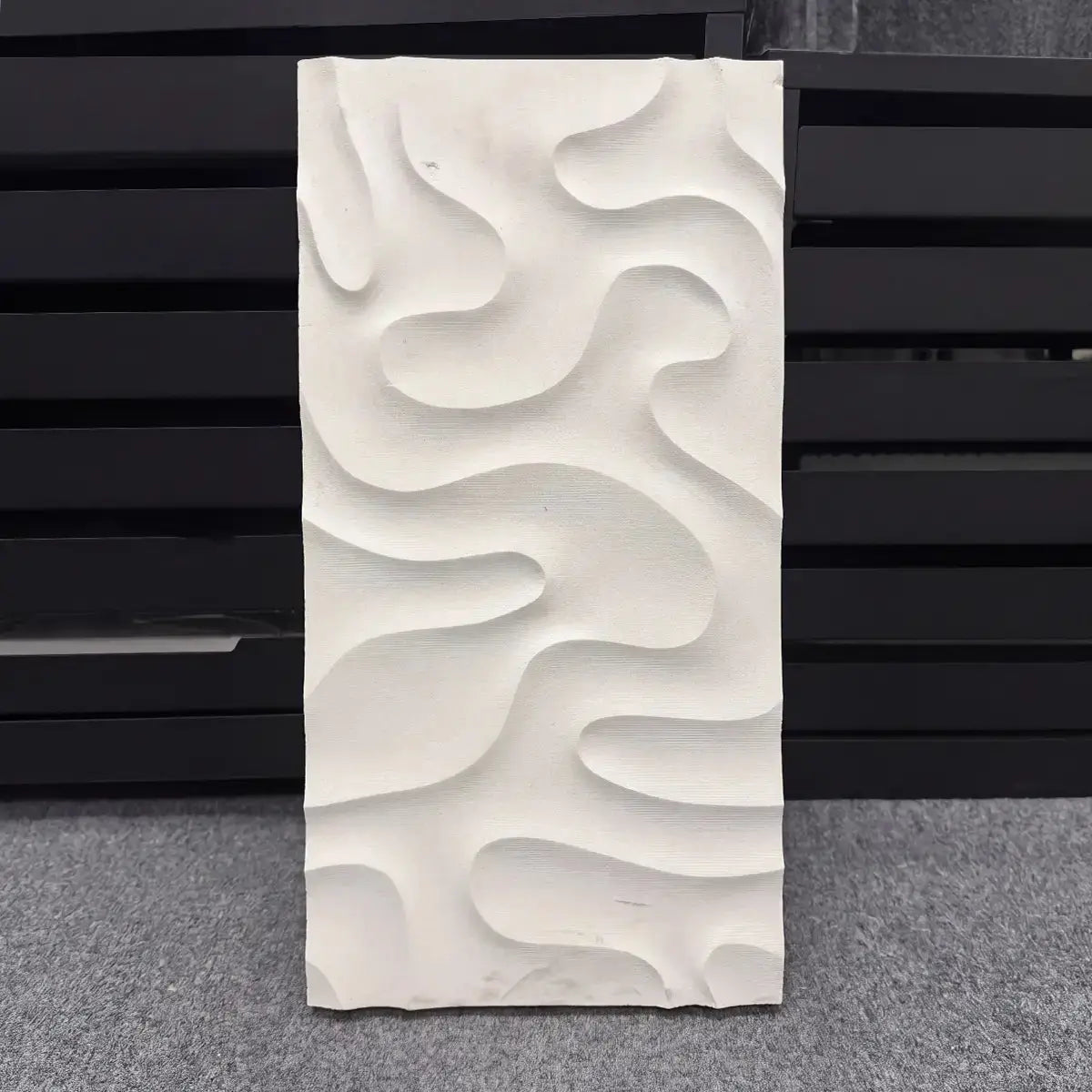 Veronica natural stone 3D wall panel sample displayed vertically against a dark background, showcasing its fluid, organic carved contour lines and sculptural relief texture.