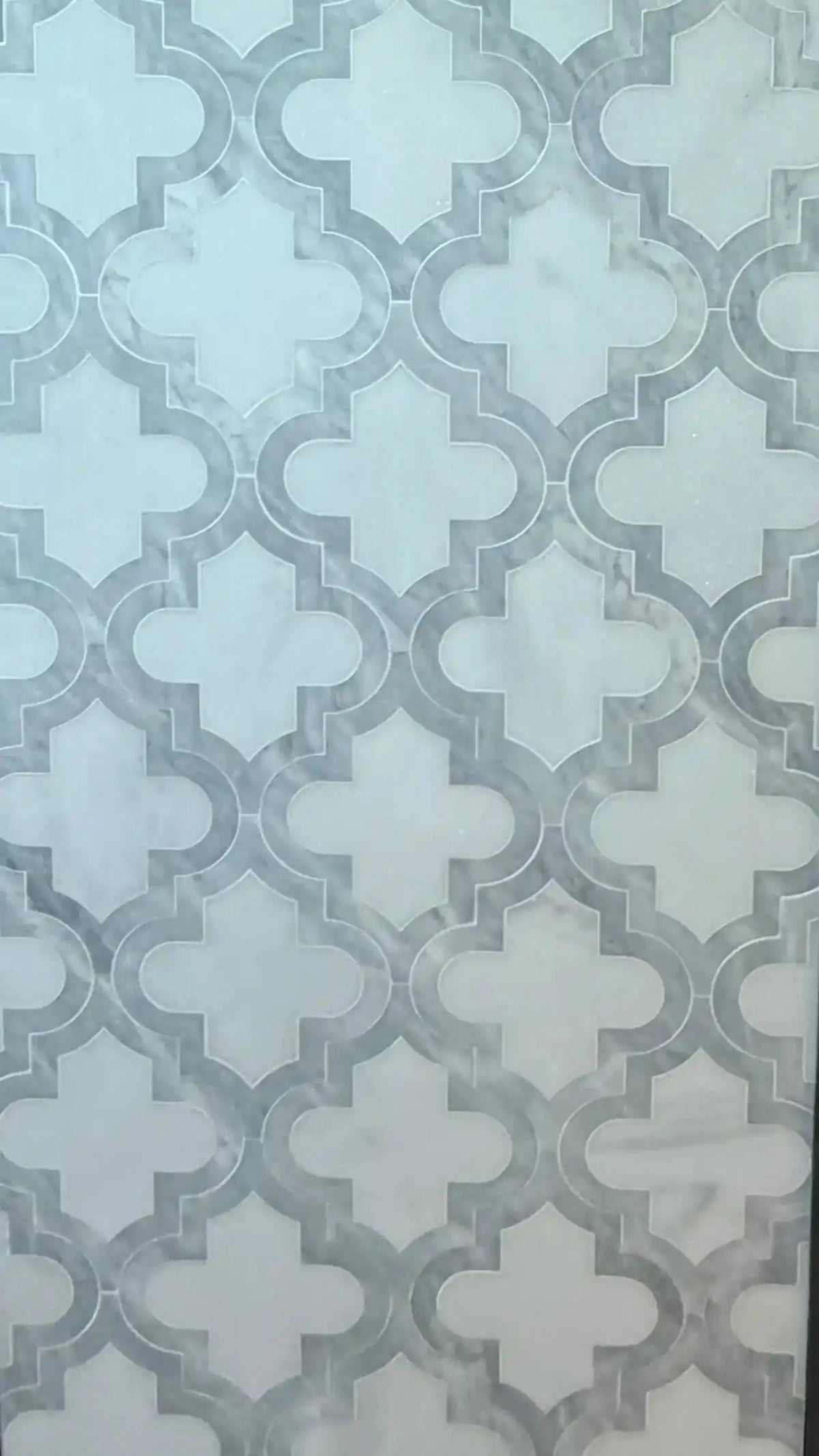 Ares natural marble mosaic tile displayed as an installed vertical sheet or wall panel, featuring an interlocking geometric quatrefoil pattern in a polished white finish with subtle grey veining.