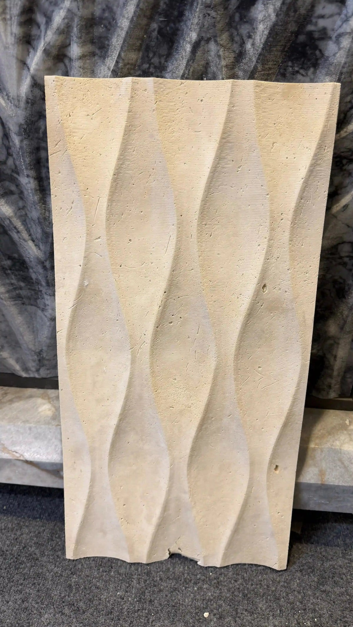 Caius natural stone 3D wall panel displayed as an individual vertical rectangular tile, featuring a sculpted wavy textured surface in a warm beige travertine finish with natural surface pores and grain variation.