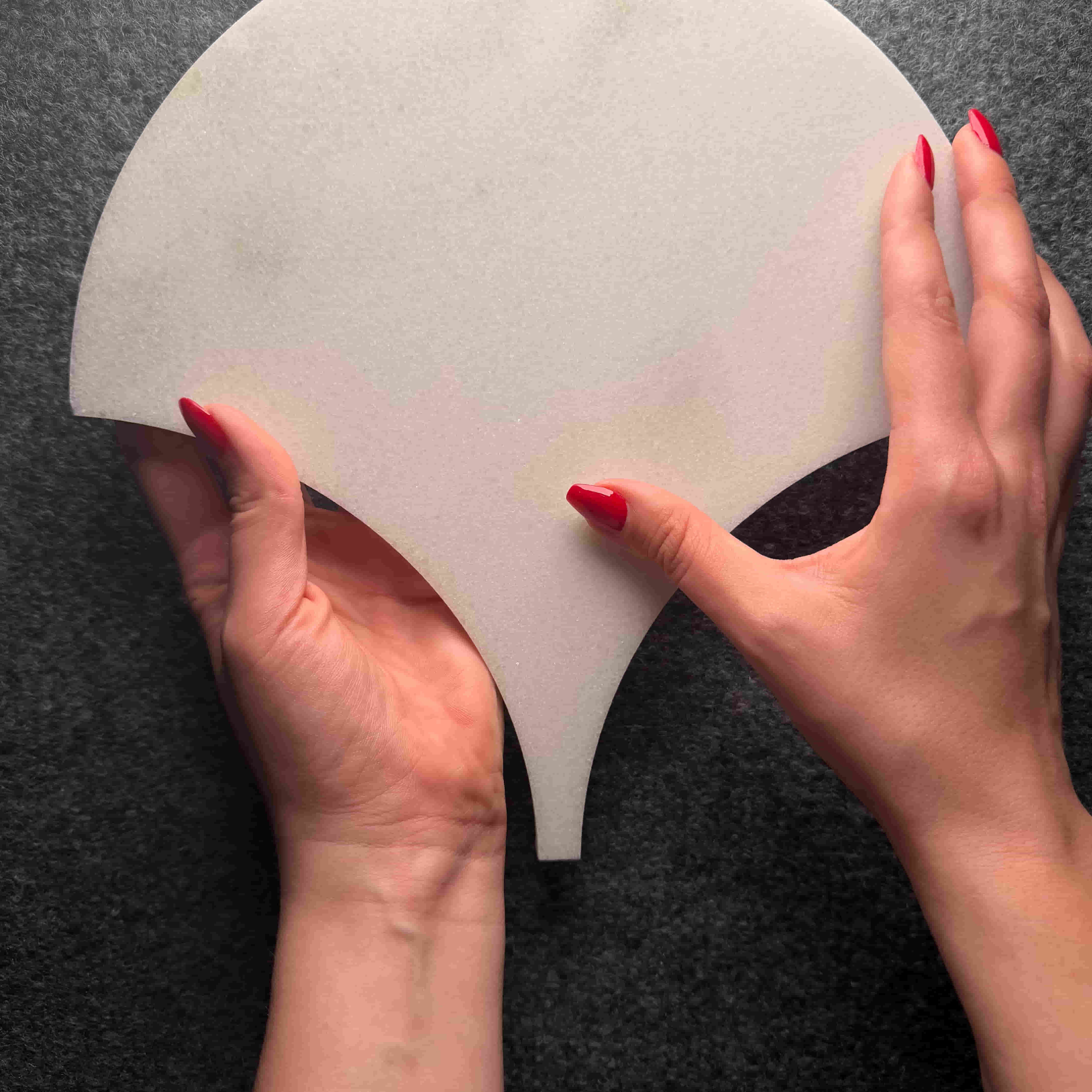 Hands holding a white silicone mold against a dark background