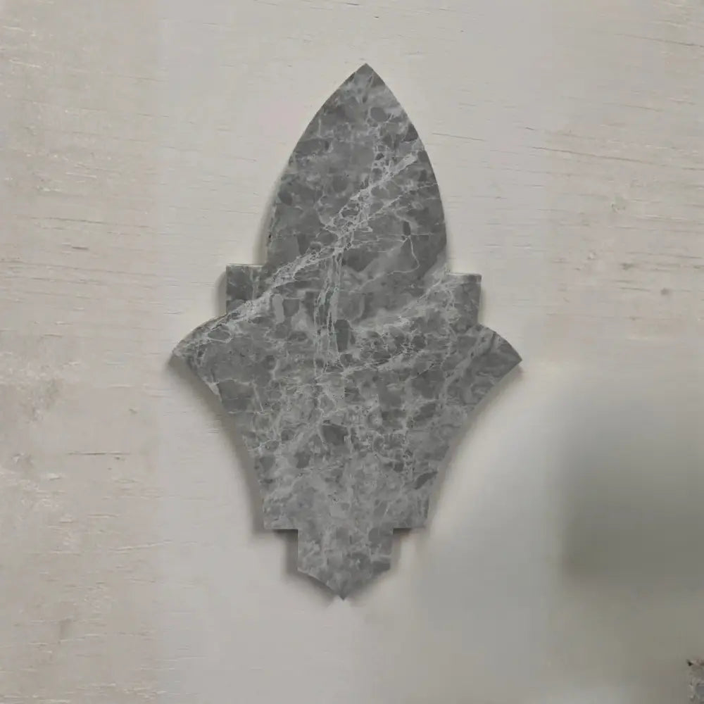Khepri marble mosaic tile featuring an ornate, pointed geometric silhouette crafted from natural grey stone with intricate veining.