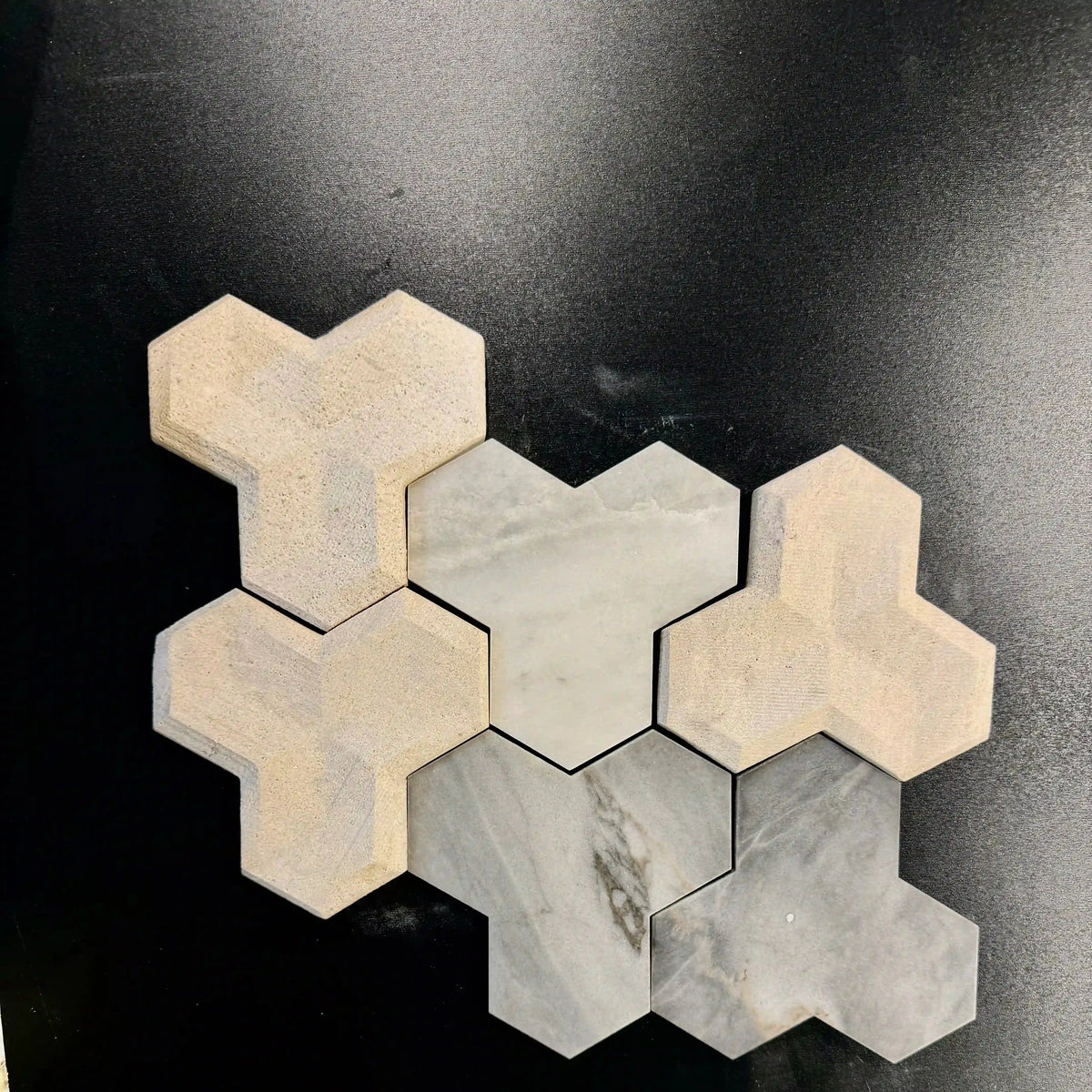 Tabu natural stone 3D wall tile sample arrangement showcasing interlocking geometric Y-shaped marble pieces in varied shades of grey, blue-grey, and white with distinct natural veining.