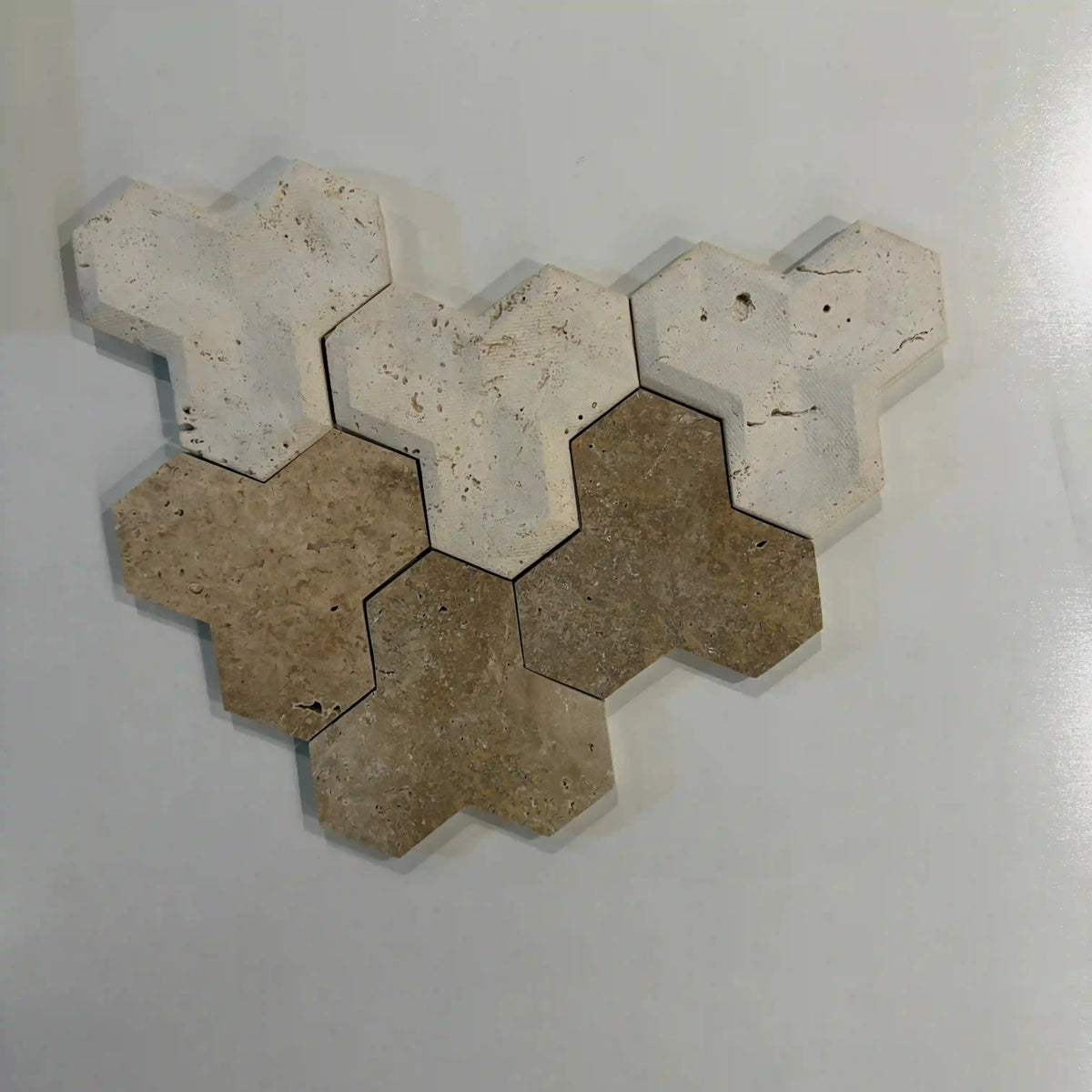 Tabu natural stone 3D wall tile sample arrangement showcasing interlocking geometric Y-shaped travertine pieces combining light beige and medium brown tones with natural porous textures.