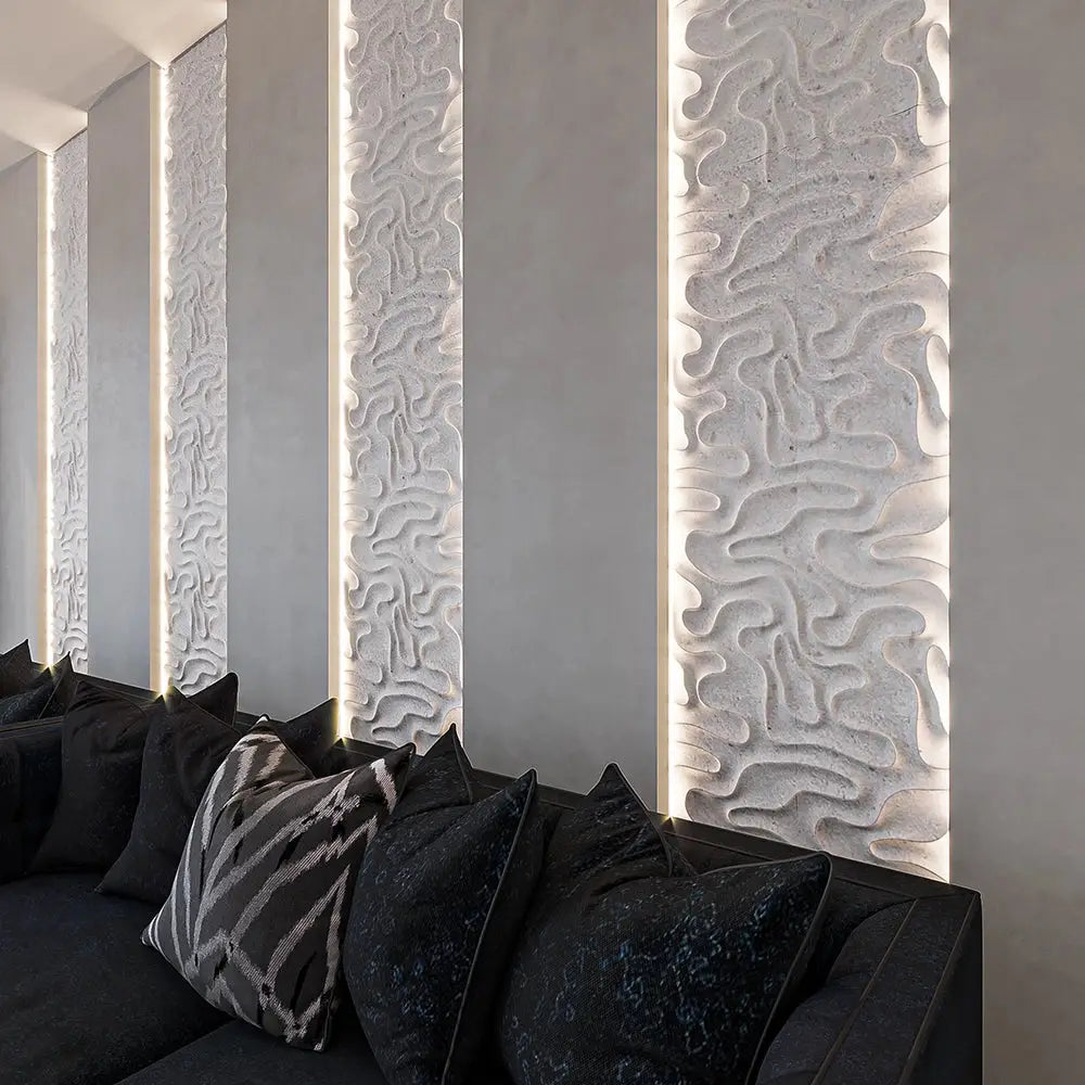 Veronica natural stone mosaic tile showcased as vertically aligned, backlit accent panels in an elegant lounge setting, emphasizing its fluid, organic carved relief pattern above a dark sofa.